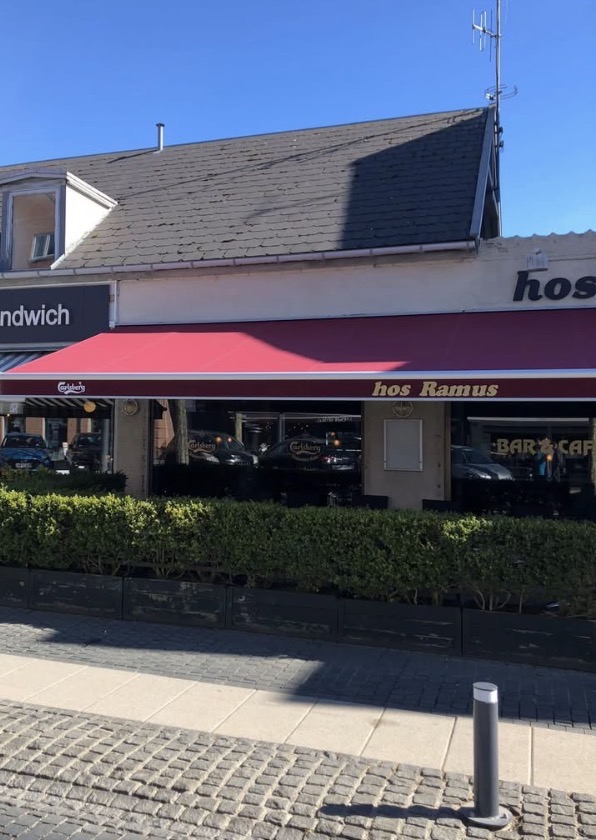 Hos Ramus' facade med rød markise i solskin